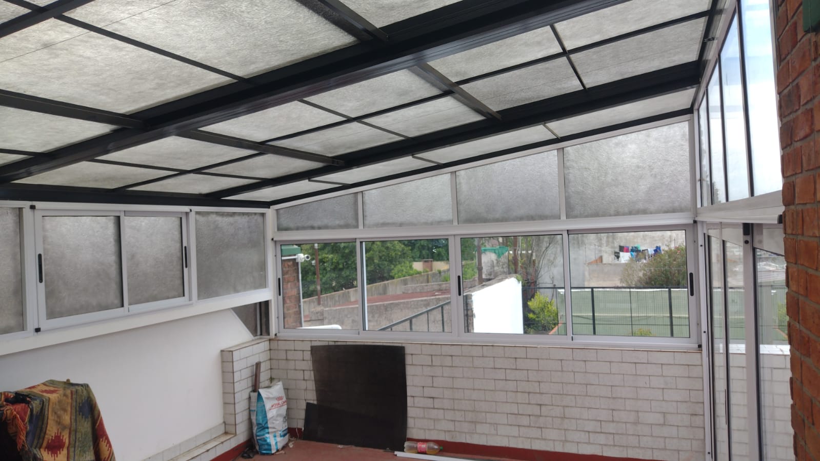 Cerramiento de terraza con ventanas de aluminio blanco y techo traslúcido